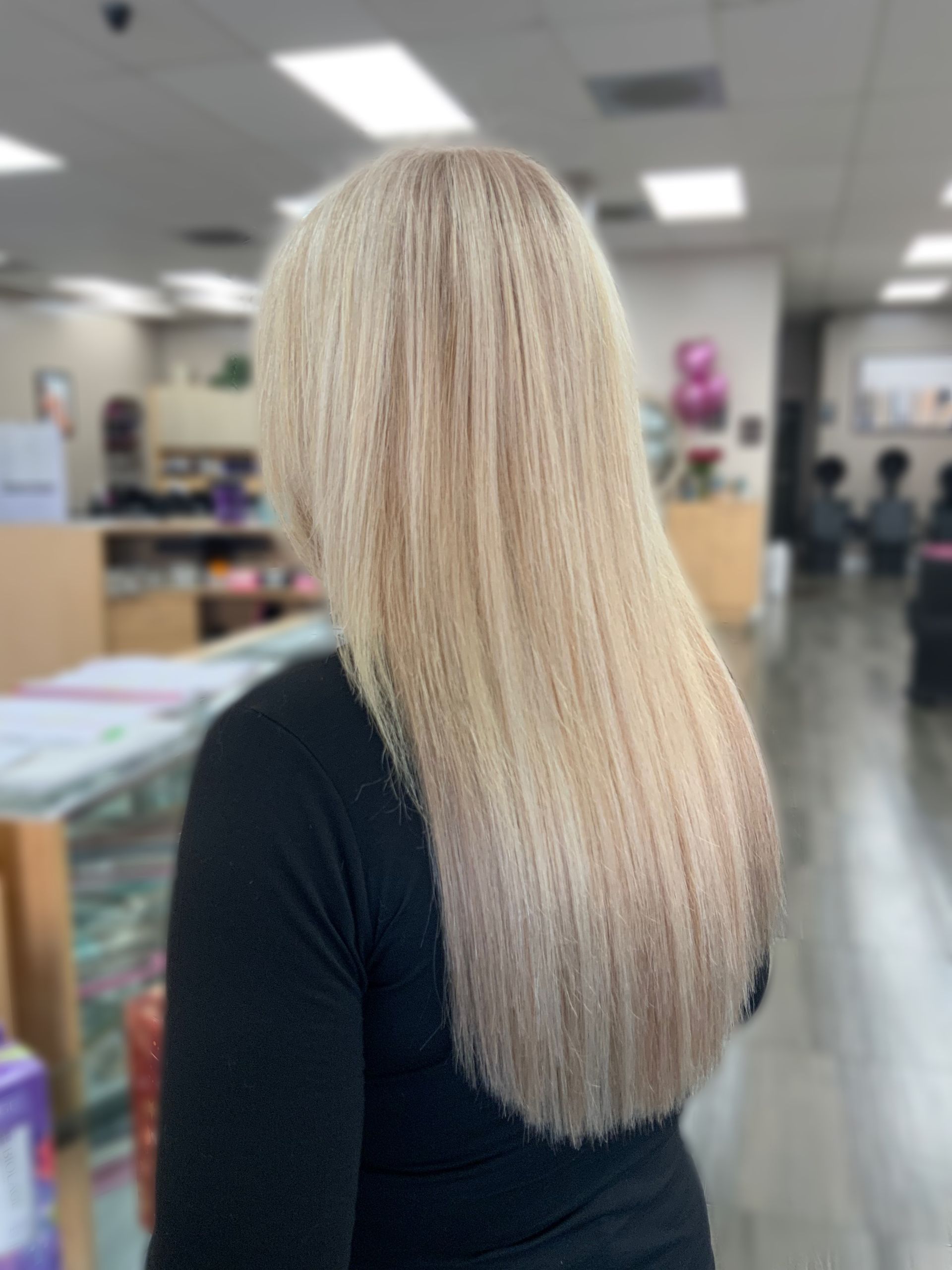 A woman with long blonde hair is wearing a black shirt