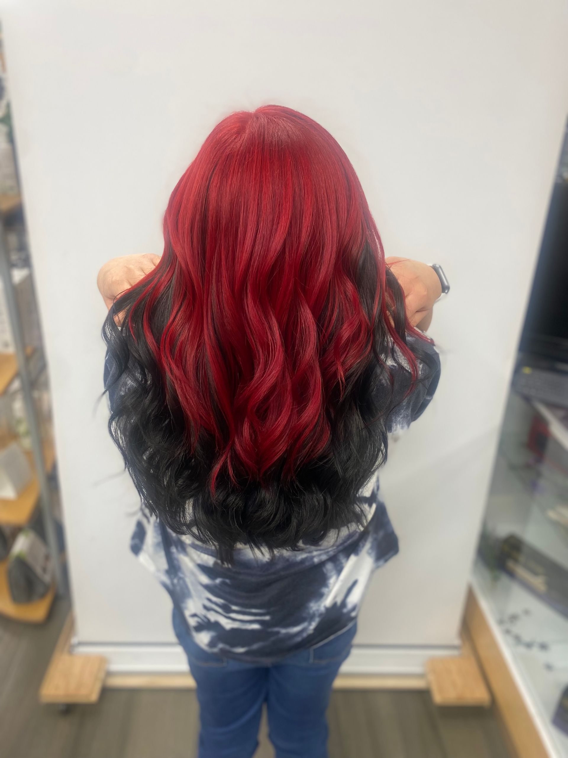 A woman with red and black hair is standing in front of a white board.