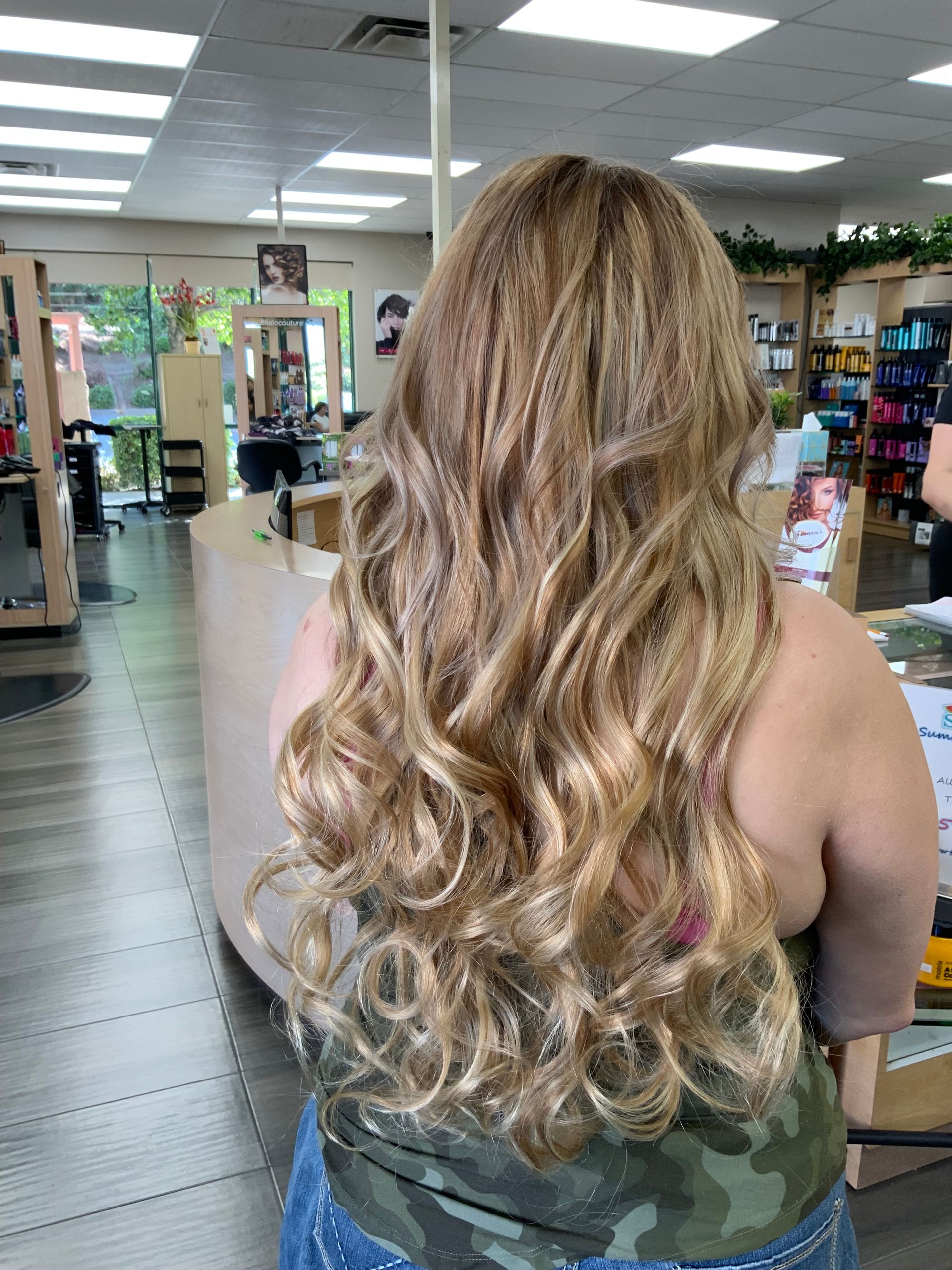 A woman with long blonde hair is standing in a salon.