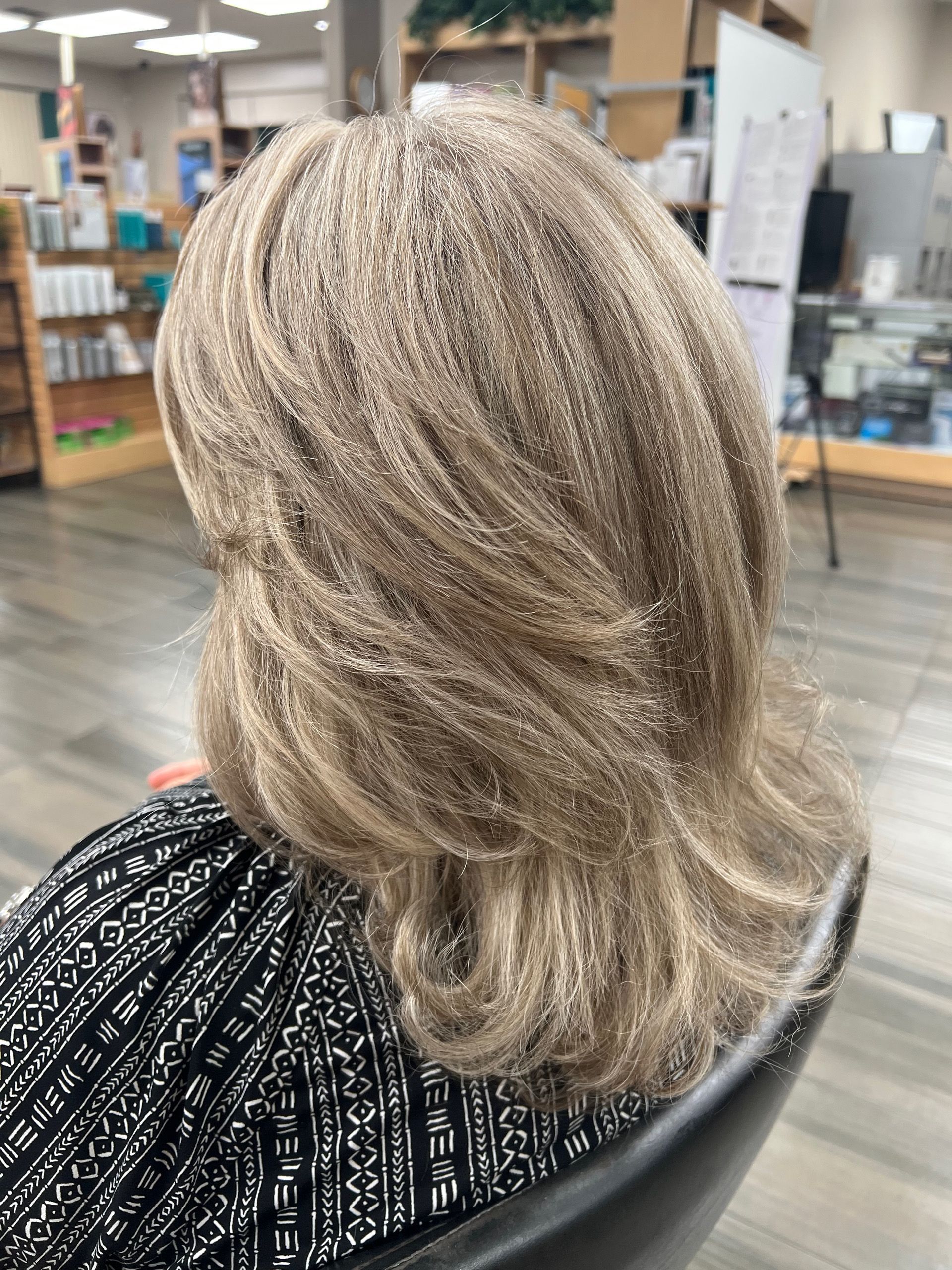 A woman wearing a wig is sitting in a chair in a salon.
