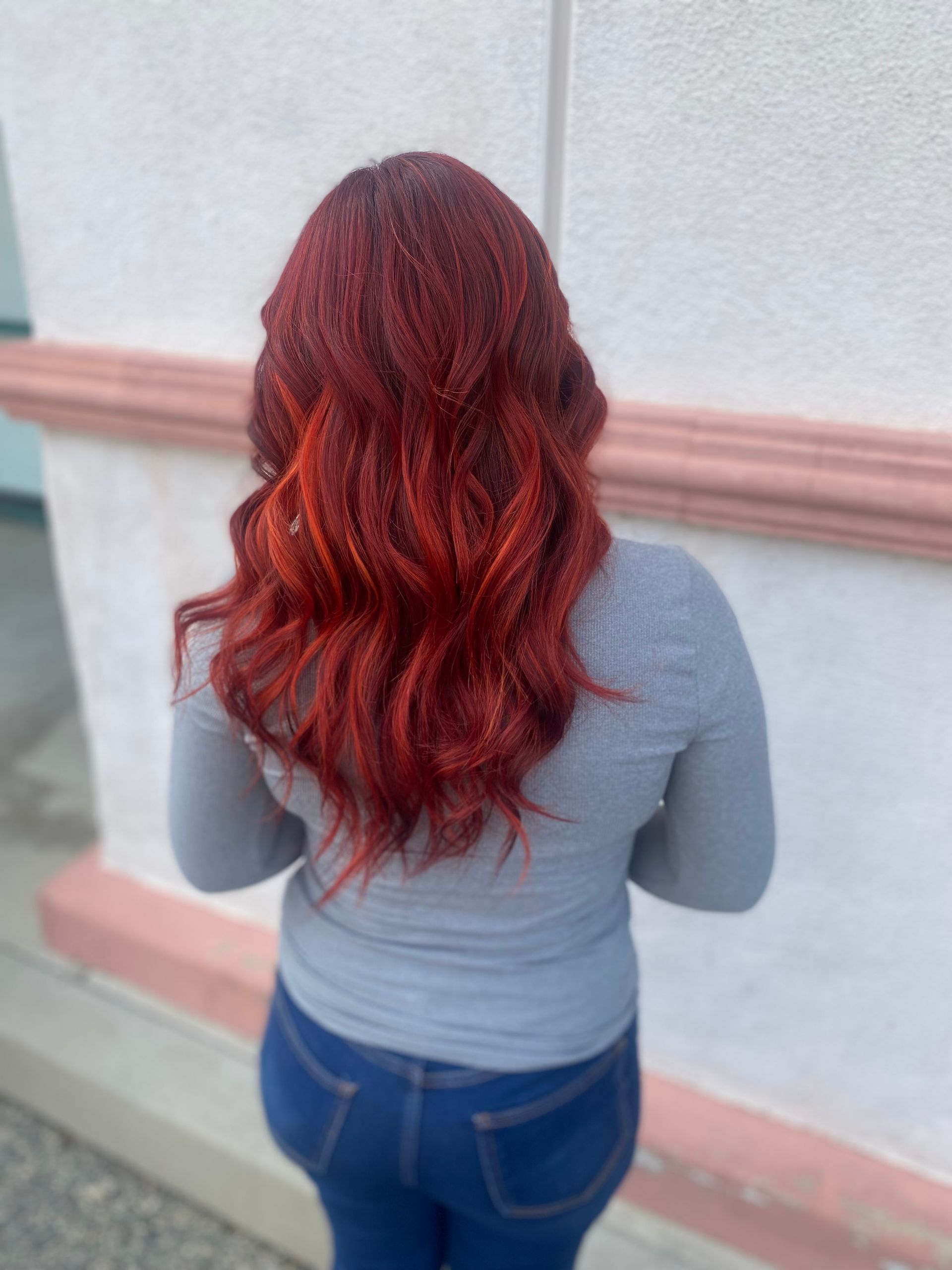 A woman with red hair is standing in front of a building.