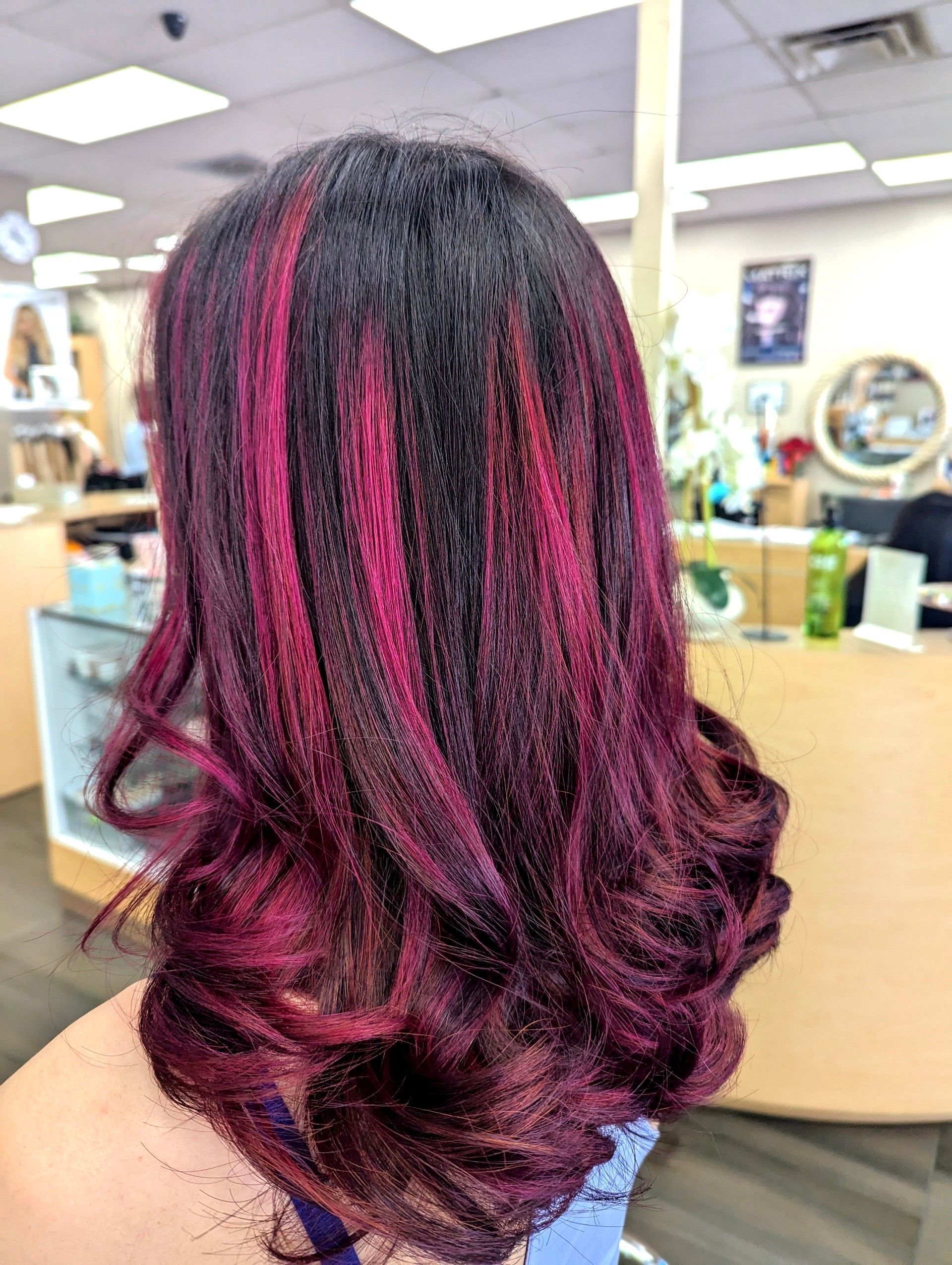 A woman with purple hair is sitting in a chair in a salon.
