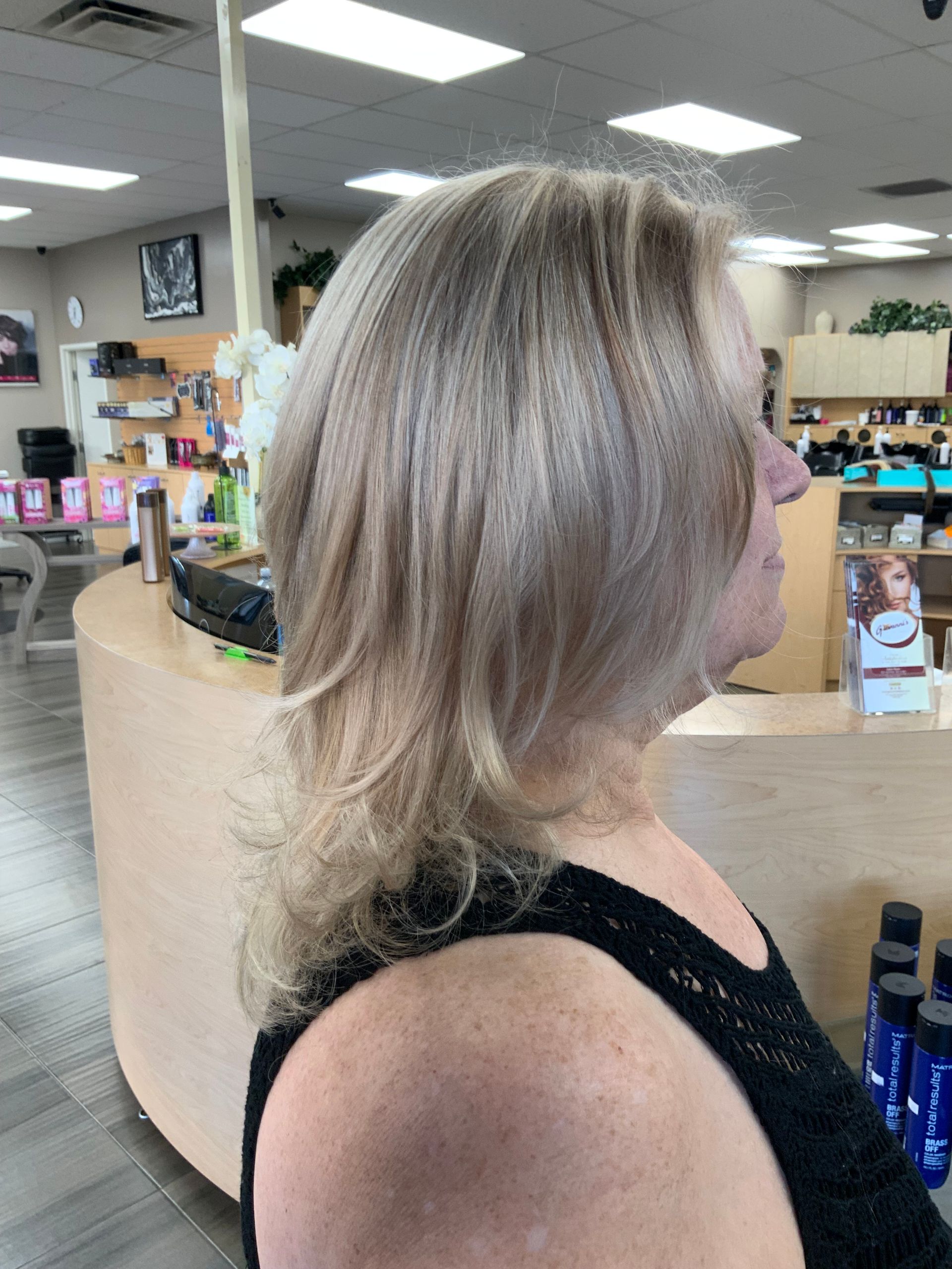 A woman with blonde hair is standing in front of a counter in a salon.