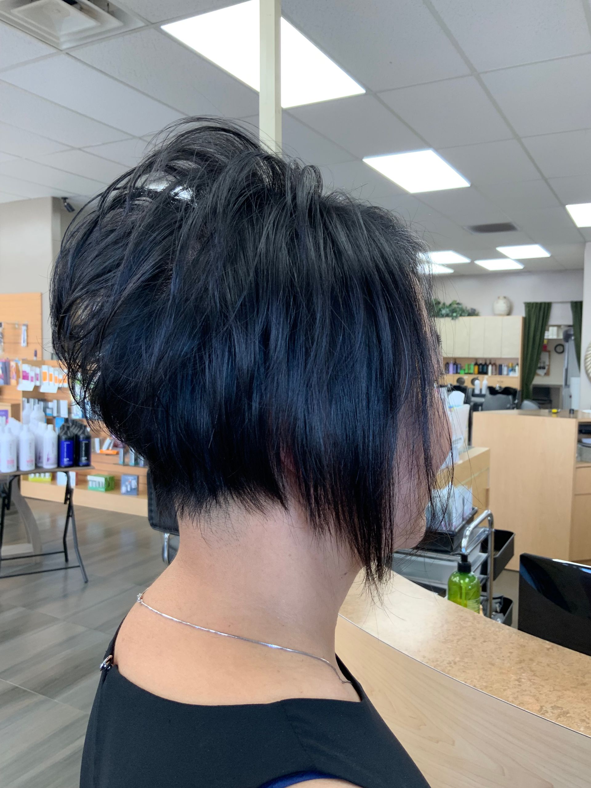 A woman with short black hair is standing in a salon.