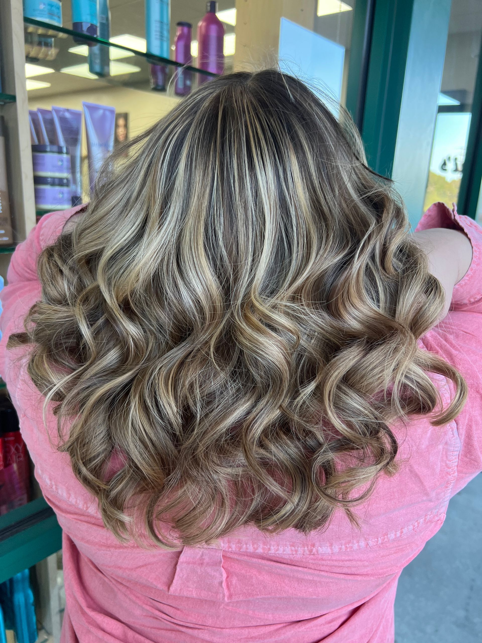 The back of a woman 's head with curly hair and a pink jacket.