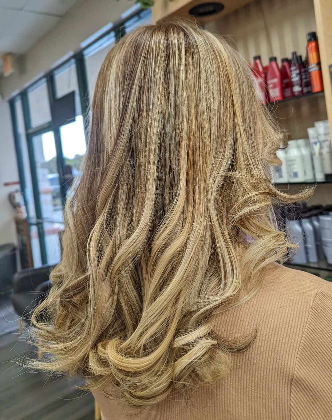 A woman with long blonde hair is standing in a salon.