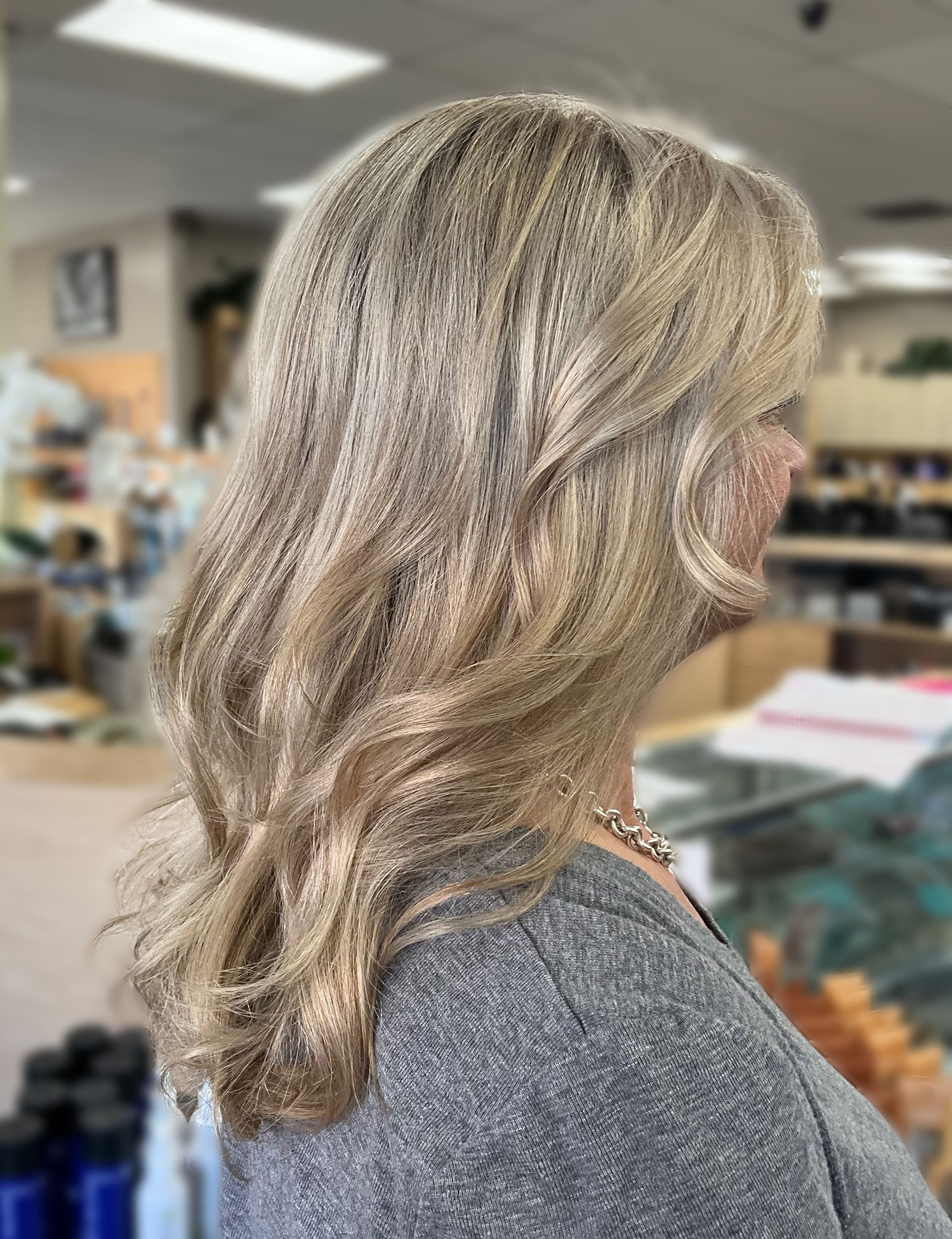 A woman with long blonde hair is wearing a grey shirt.