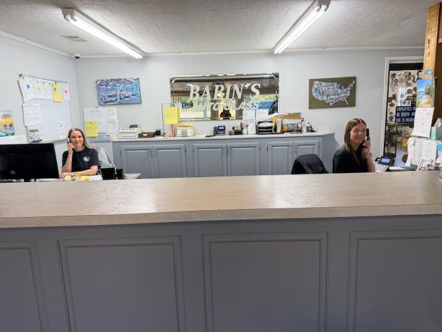 Two women at a counter in an office, one on the phone. 