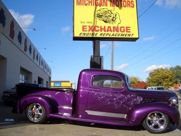 Purple custom pickup truck parked outside Michigan Motors auto shop.