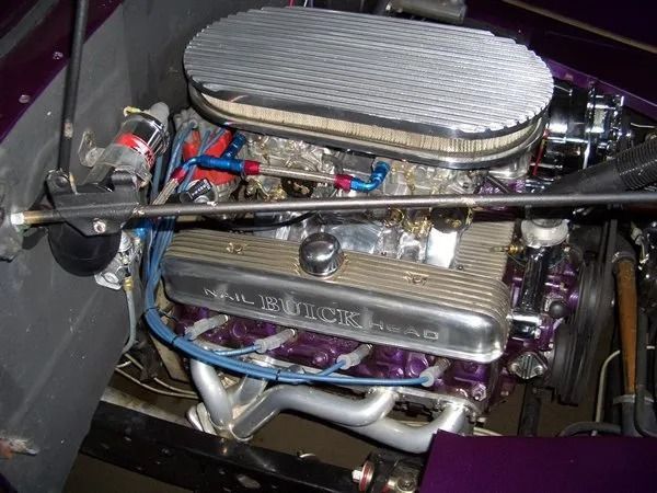 Purple Buick V8 engine in a vehicle. Chrome air cleaner and valve covers. Blue fuel lines.