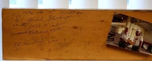 Wooden plank with handwritten notes and a photograph.