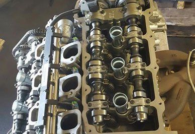 Engine cylinder head with camshafts and valve springs visible.