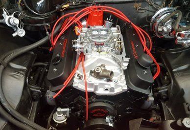 Black Chevrolet engine with red wires, and chrome carburetor.