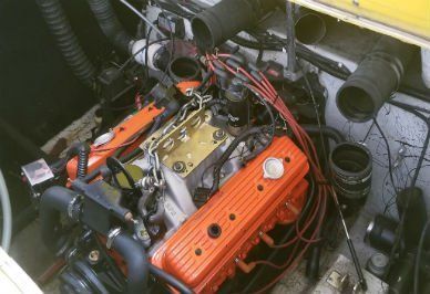 Engine bay of a boat with an orange engine and black components. Various wires and hoses visible.