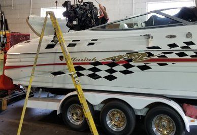 Boat on a trailer with an engine being worked on, in a repair shop.
