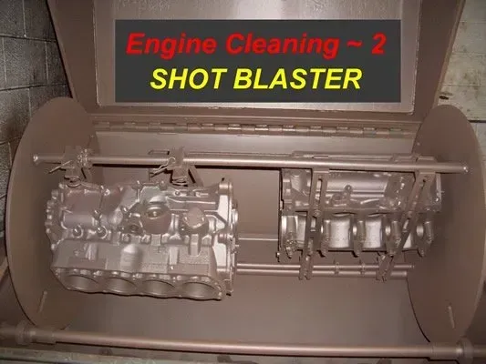 Shot blaster cleaning engine parts. Brown machine, parts rotating inside.