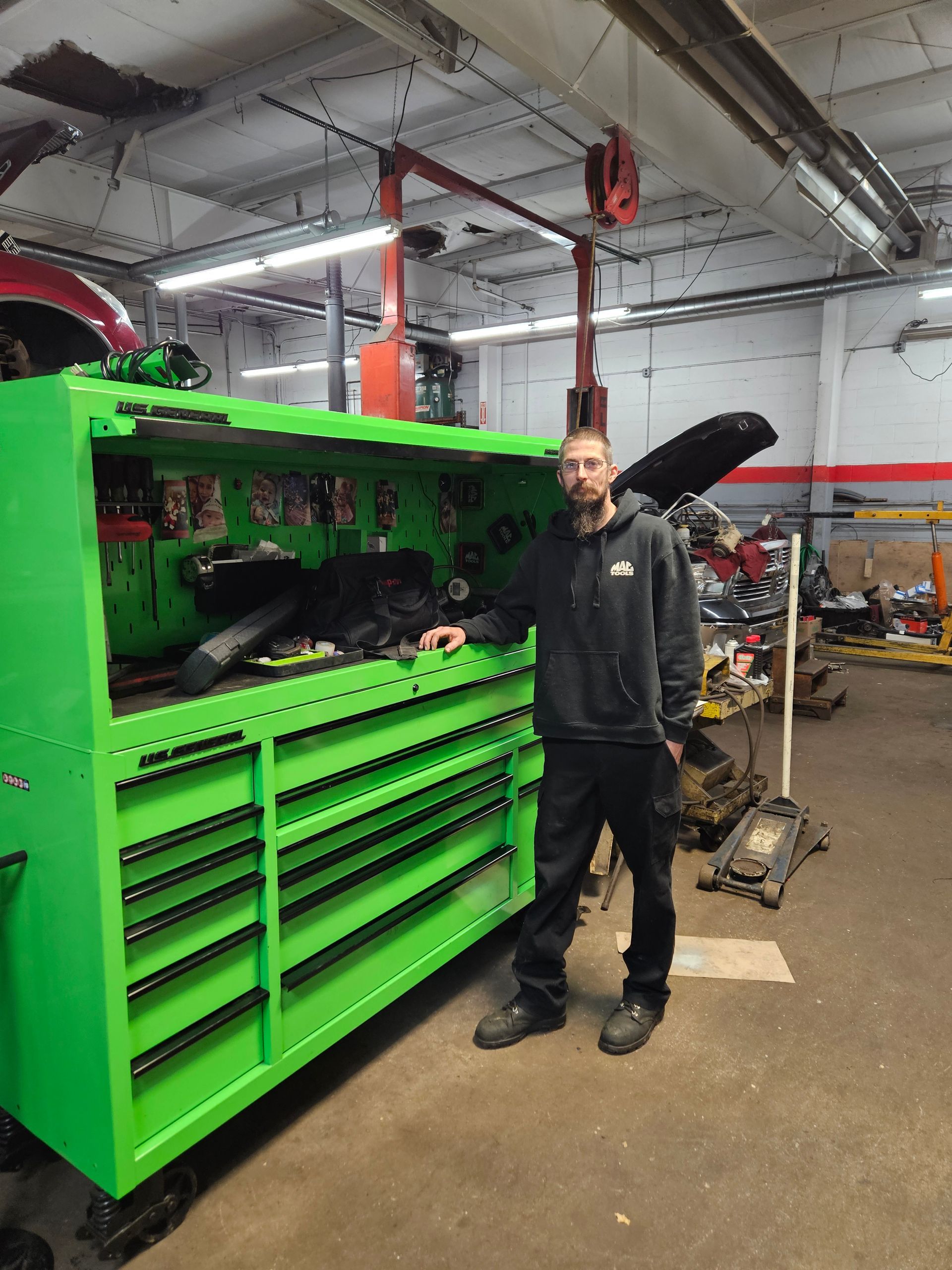 Man standing next to a bright green toolbox in a garage setting.
