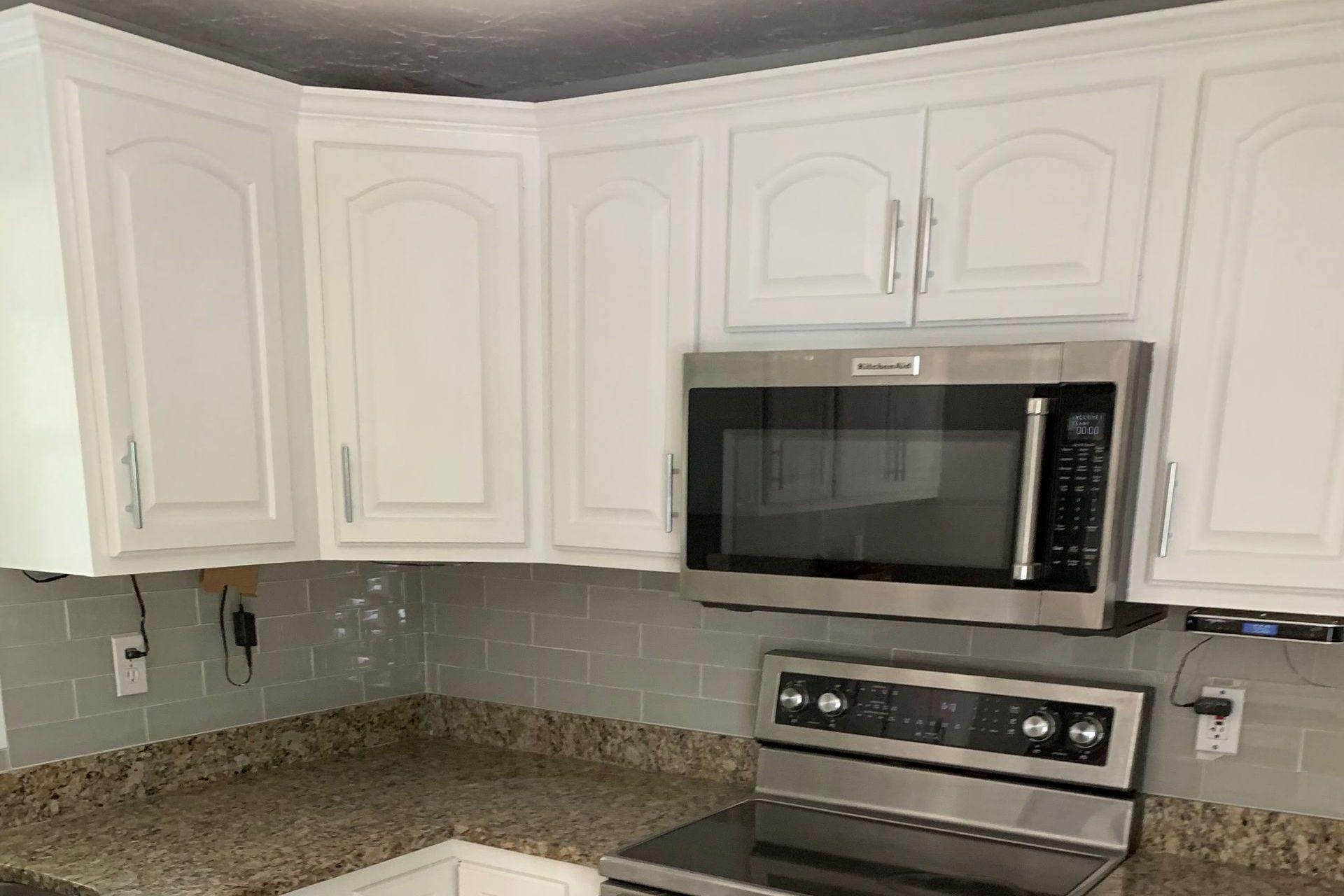 A kitchen with white cabinets , a stove , and a microwave.