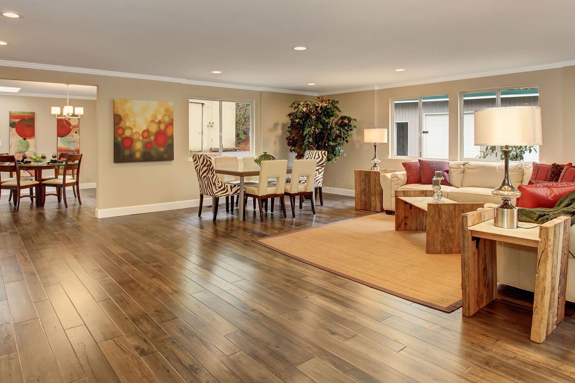 A living room with hardwood floors and a dining room in the background