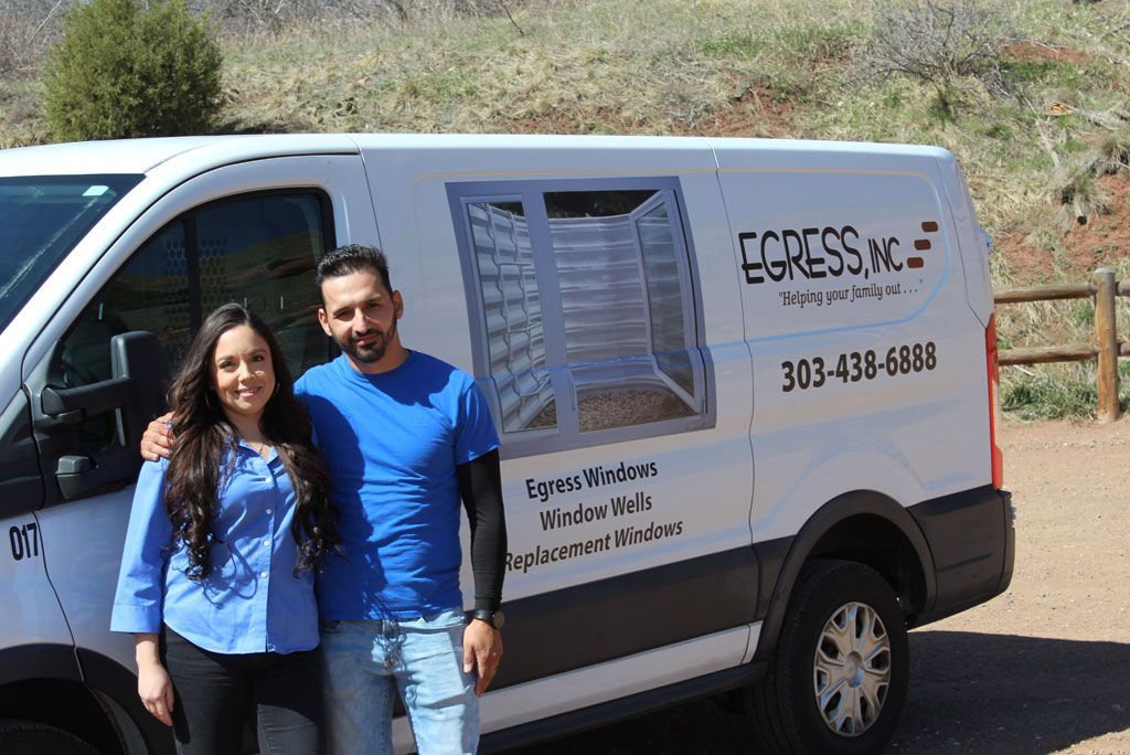 A man and a woman are standing in front of a white van.