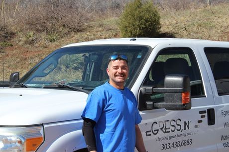 A man in a blue shirt is standing in front of a white truck.