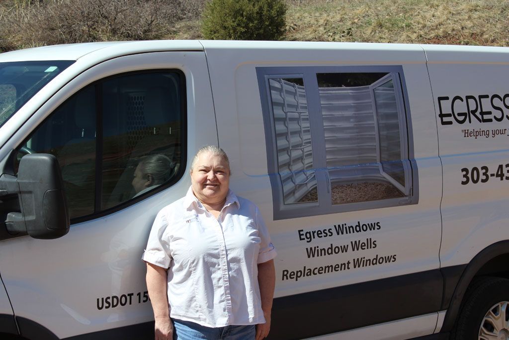 A woman is standing in front of a white van that says Egress.