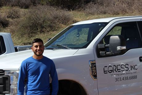 A man in a blue shirt is standing in front of a white truck.