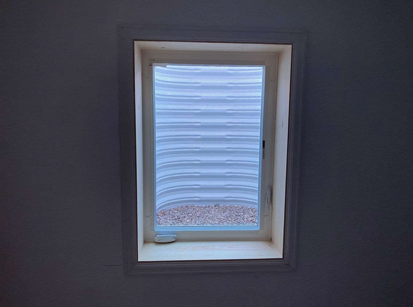 A window in a room with a striped window covering.
