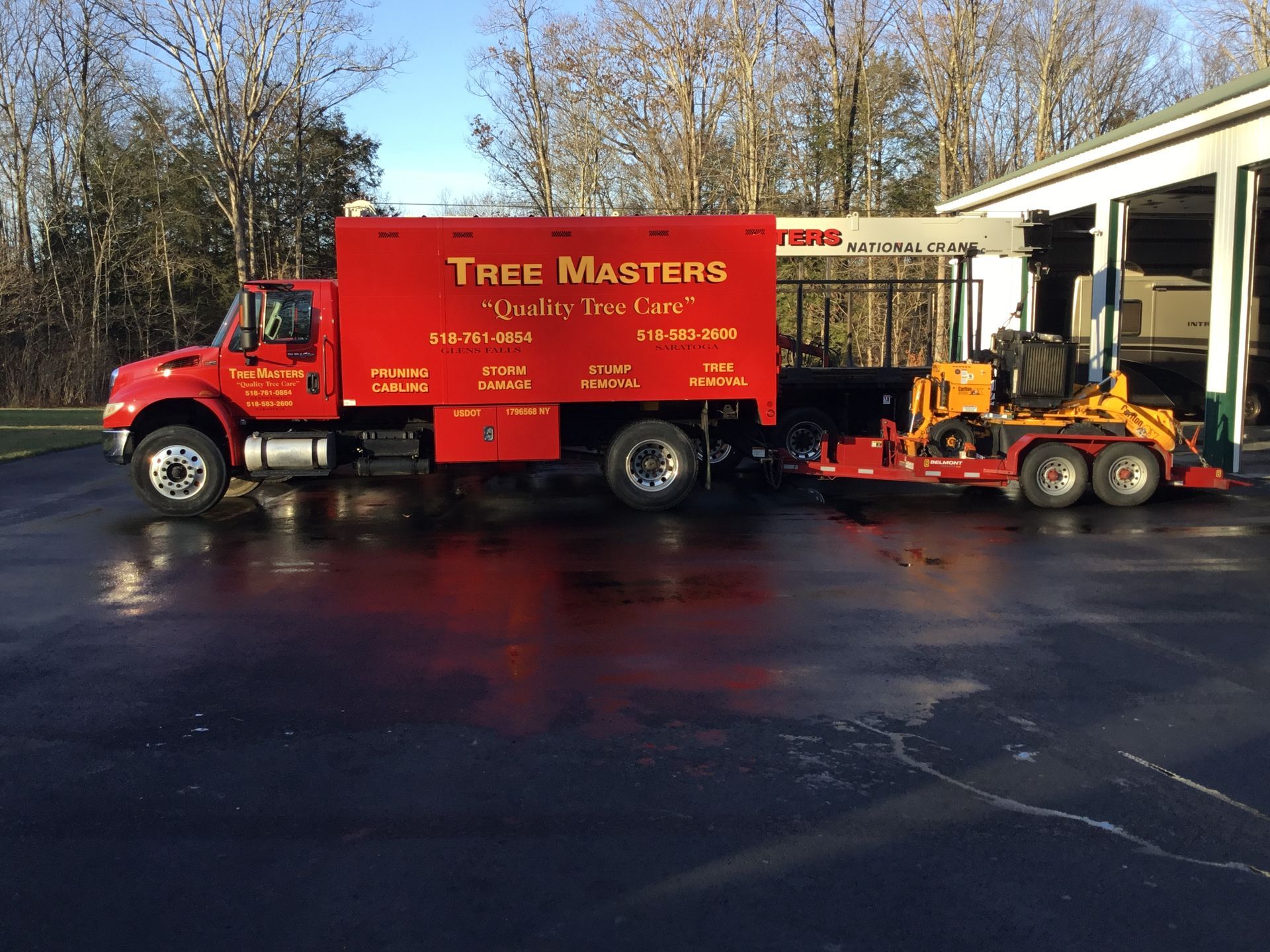 A red truck with a trailer attached to it is parked in a parking lot