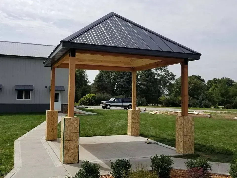 A gazebo with a black roof is sitting in front of a building.