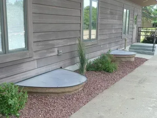 A house with a walkway leading to the front door and a window well.