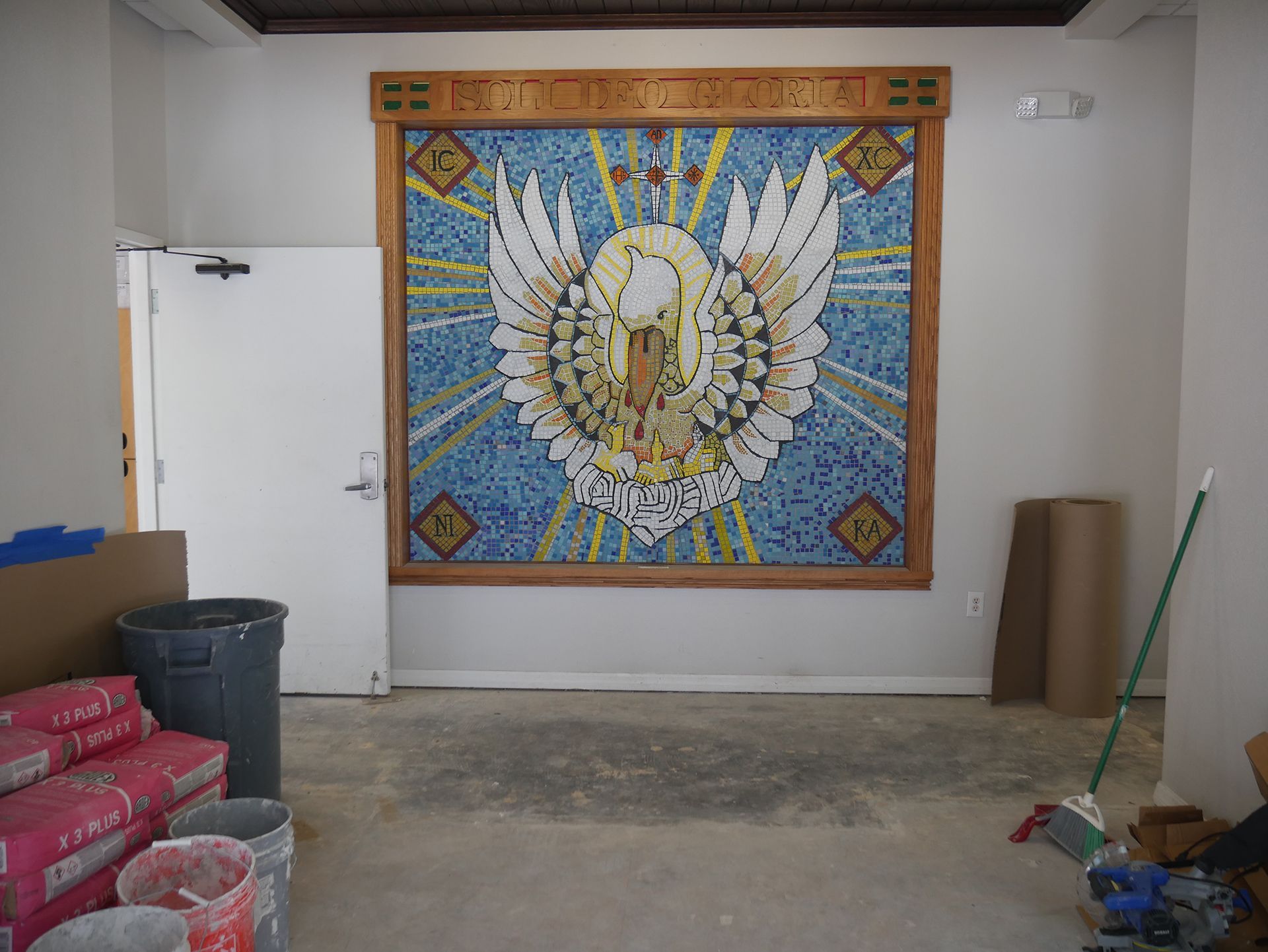 An empty room with a mosaic of a swan on the wall
