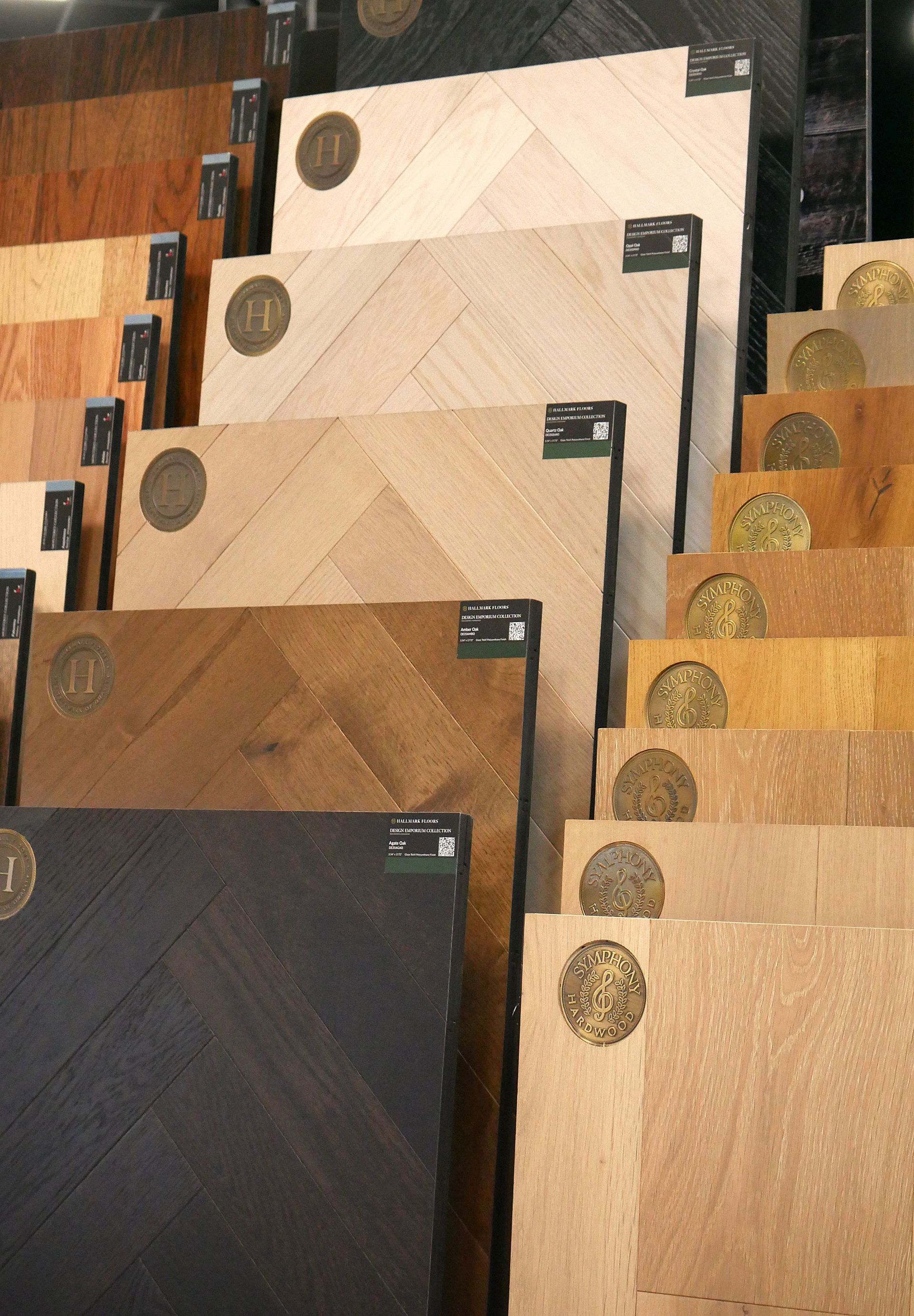 Wooden floor samples in various colors and patterns, stacked on display. Different shades range from dark brown to light beige.