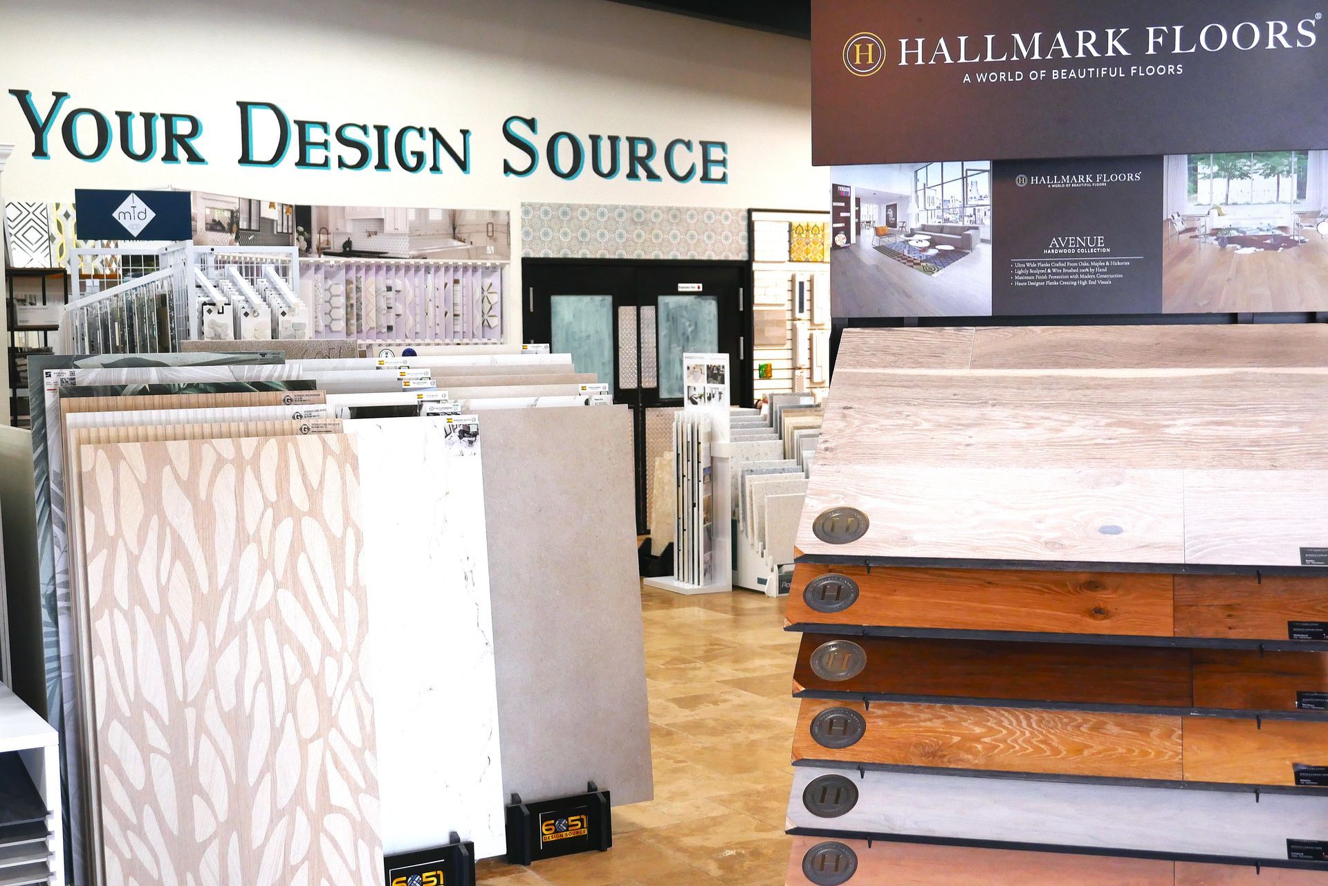 A flooring showroom with display samples. Displays include hardwood and tile options. Sign reads 