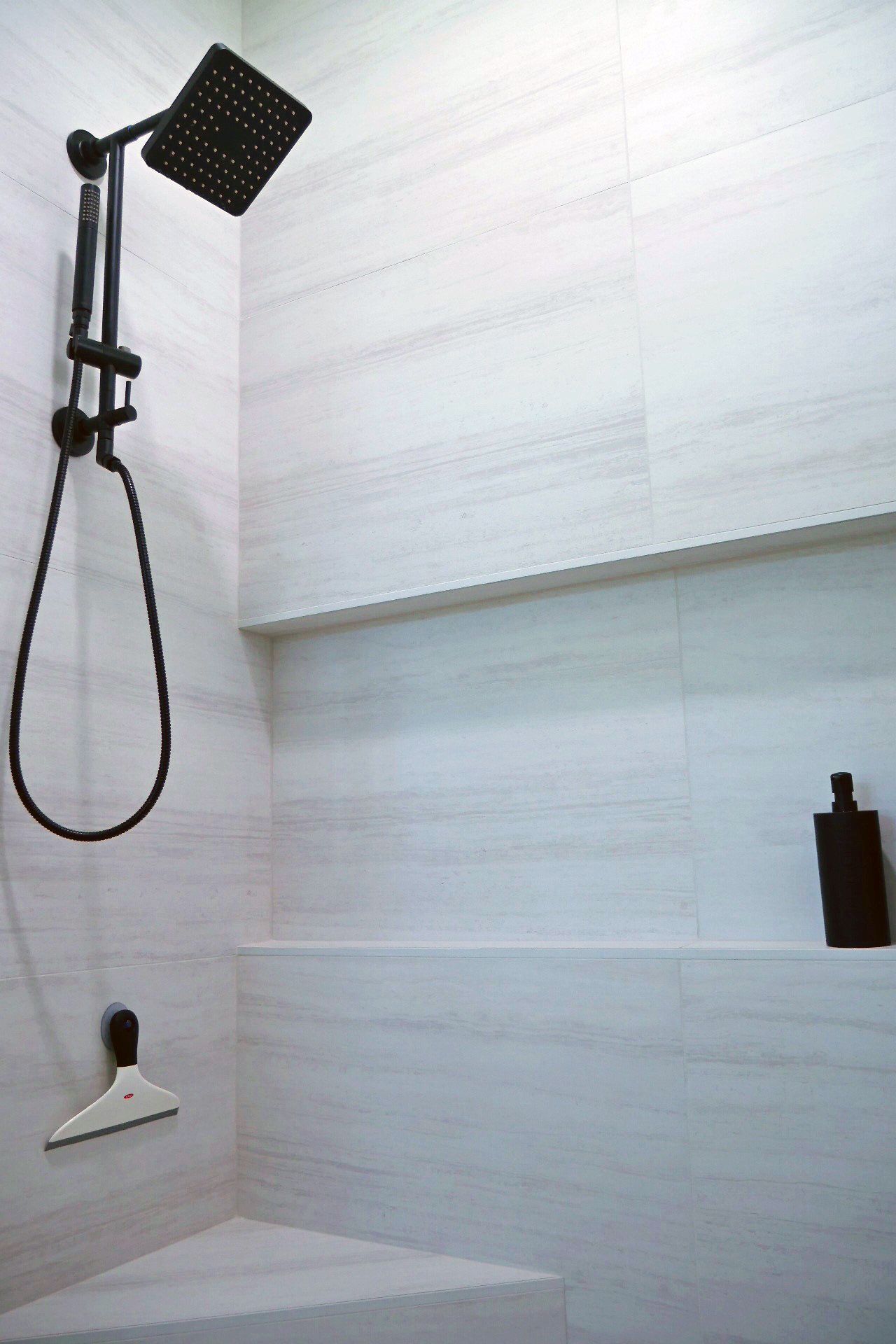 A shower head is hanging from the ceiling in a bathroom
