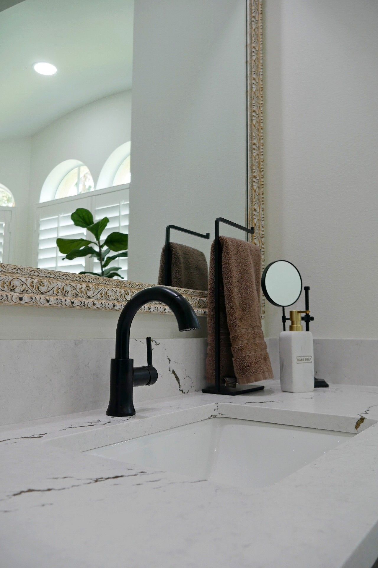 A bathroom sink with a black faucet and a mirror