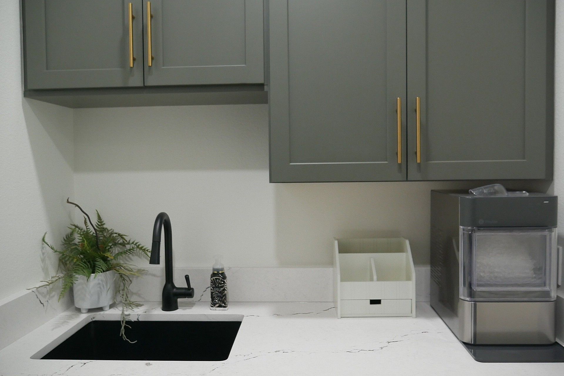 A kitchen with gray cabinets and a black sink