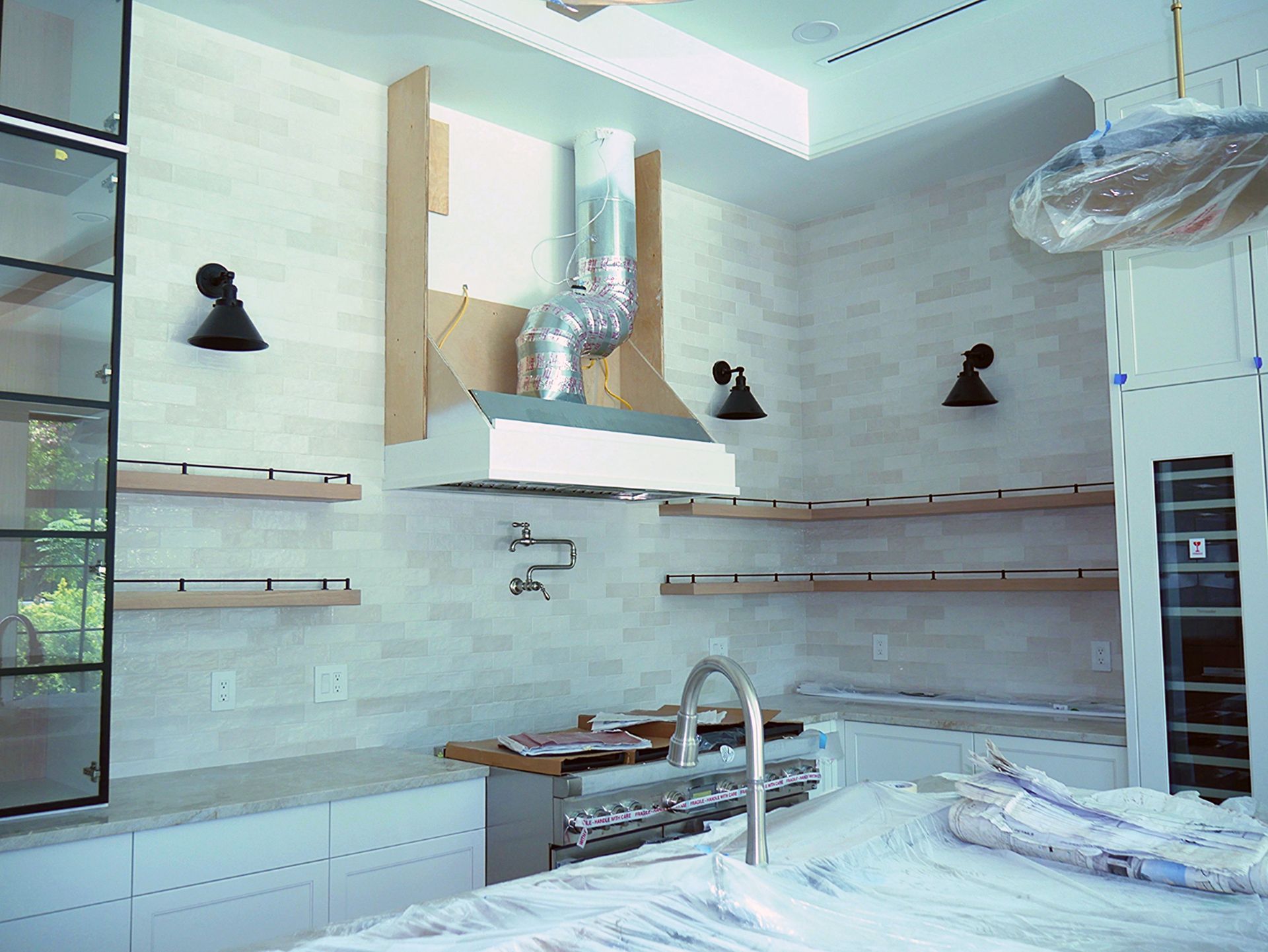 A new kitchen with white cabinets, a stove, a sink, and a hood