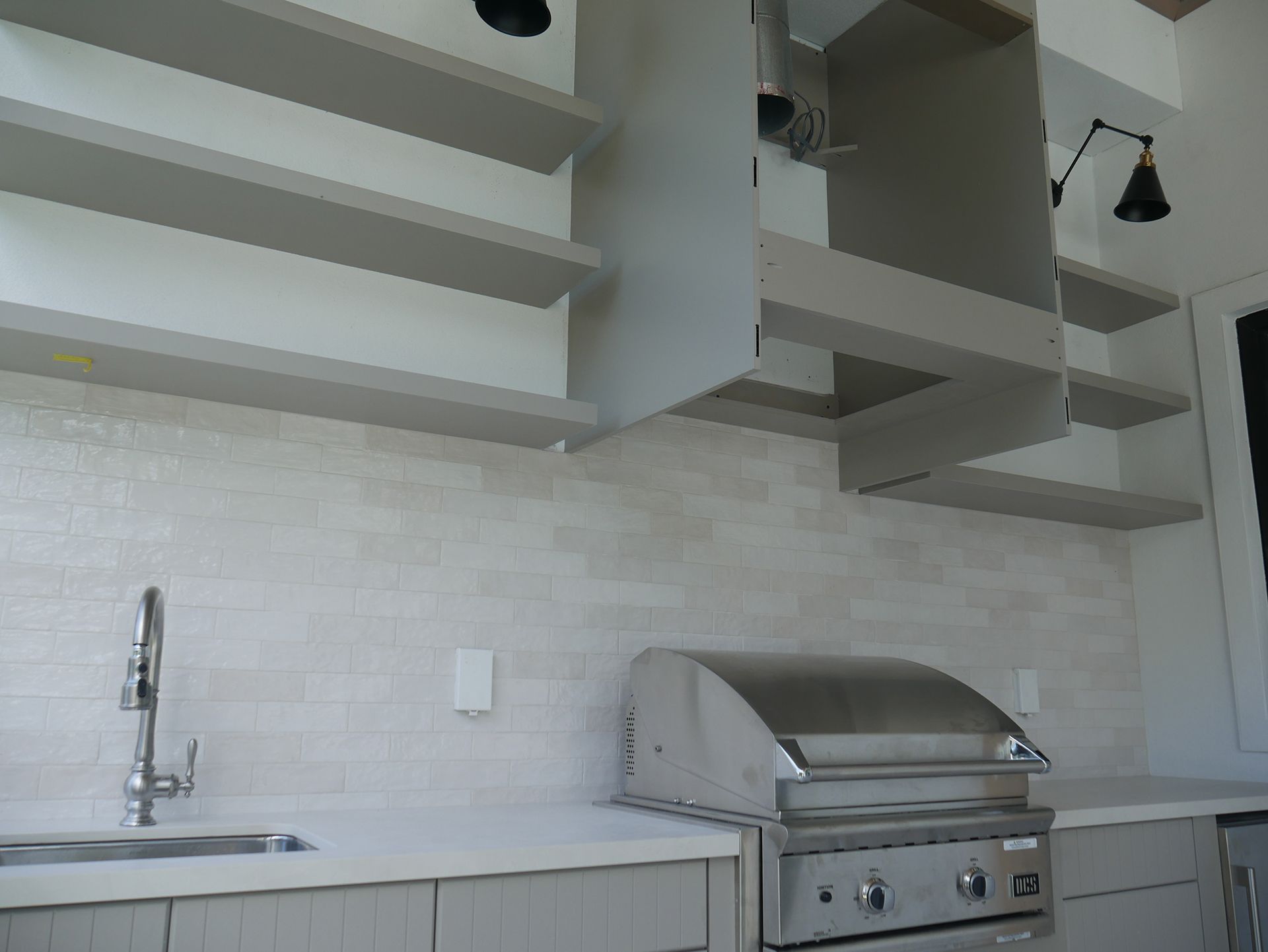 A kitchen with a stainless steel grill and a sink