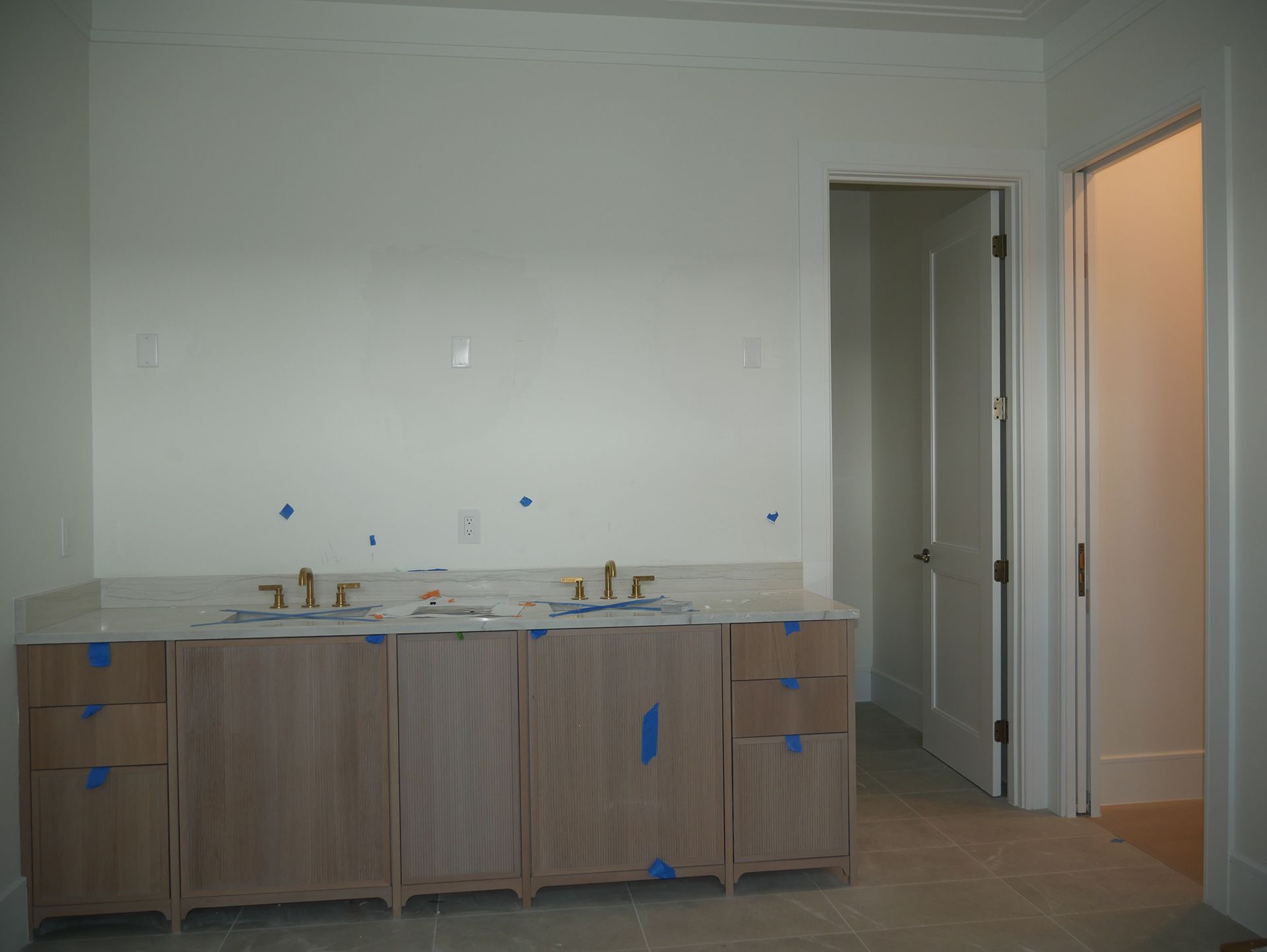 A bathroom with two sinks and a door leading to a hallway