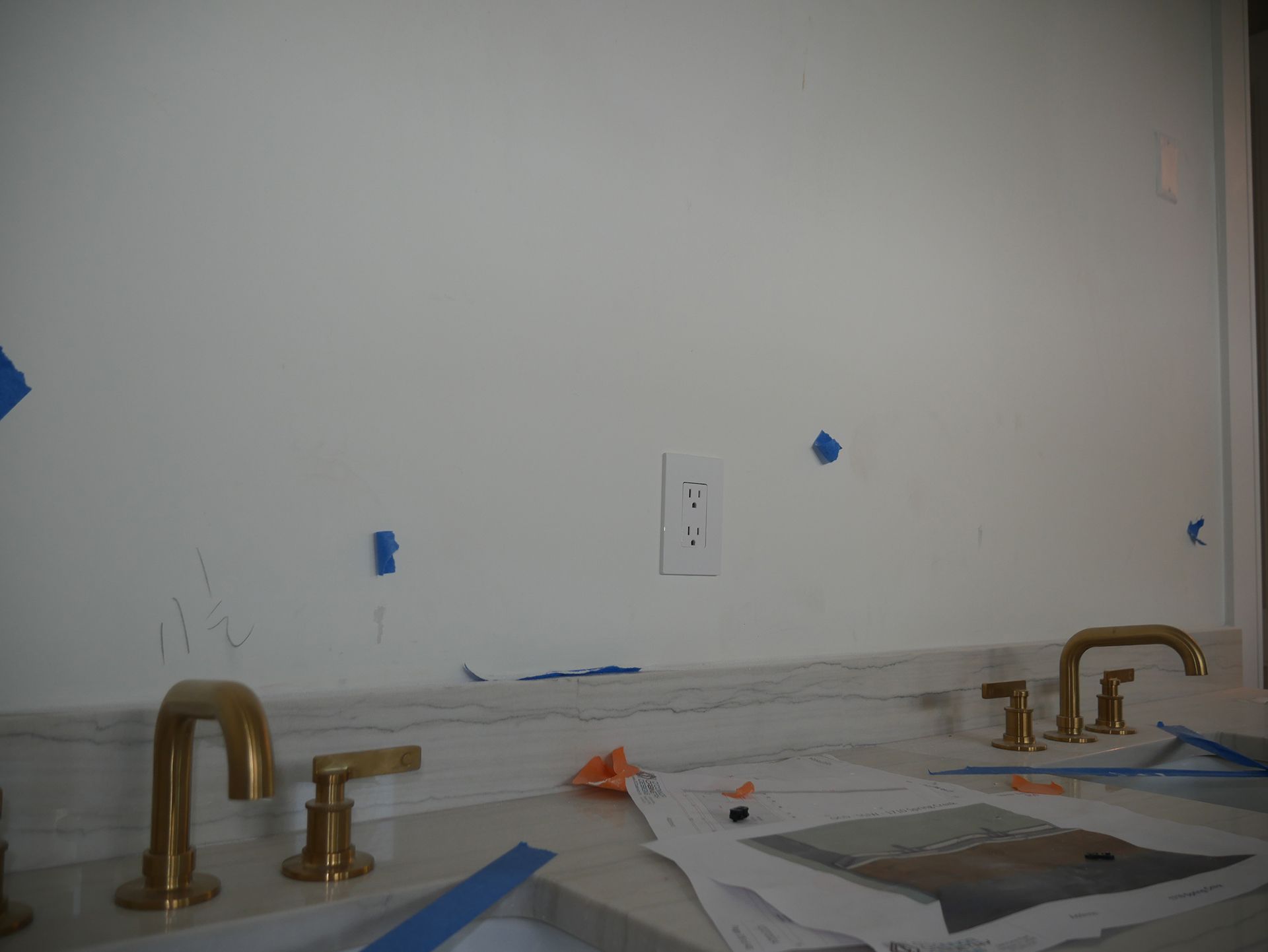 A bathroom sink with gold faucets and a white wall