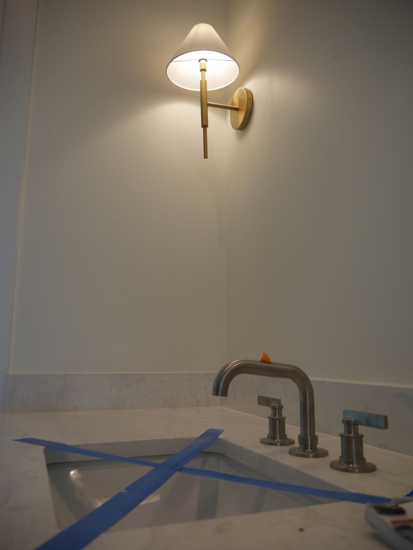 A bathroom with a sink and a lamp on the wall