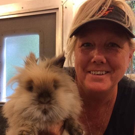 A woman in a hat is holding a fluffy rabbit