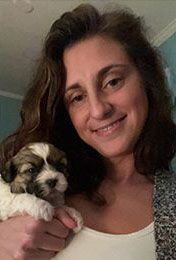 A woman is holding a puppy in her arms and smiling.