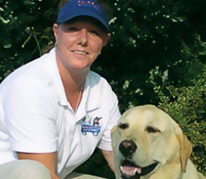 A woman in a white shirt is sitting next to a yellow dog.