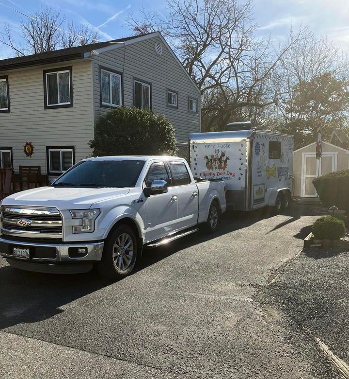 A white truck and trailer are parked in front of a house