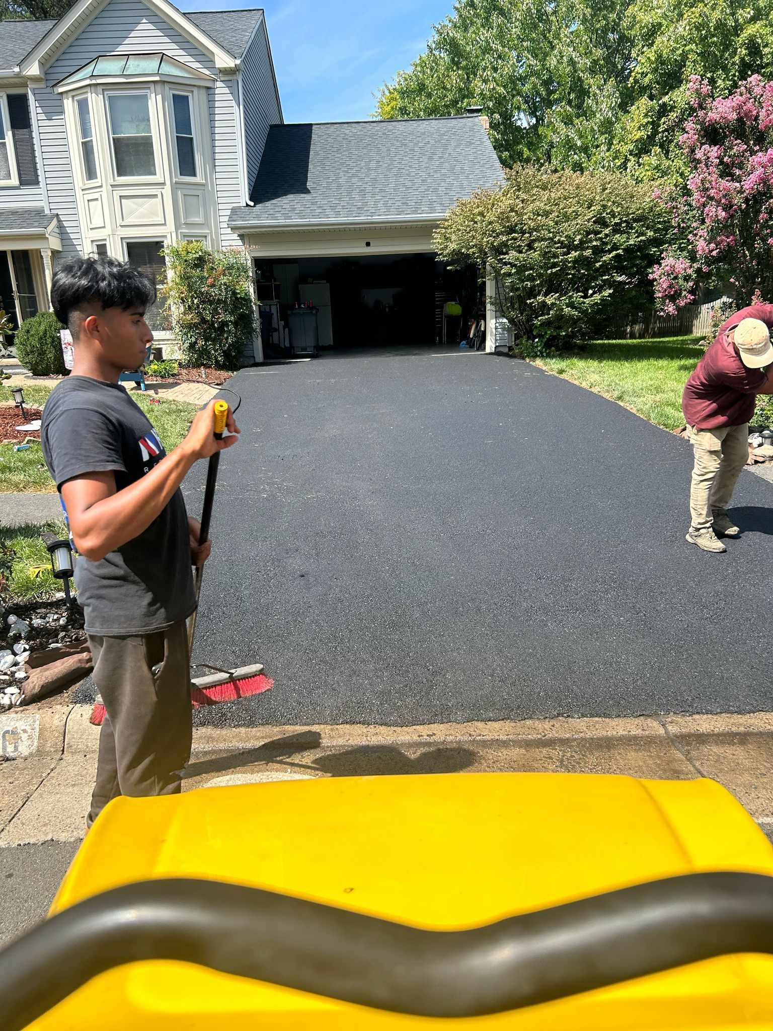A man is standing in front of a house holding a shovel.