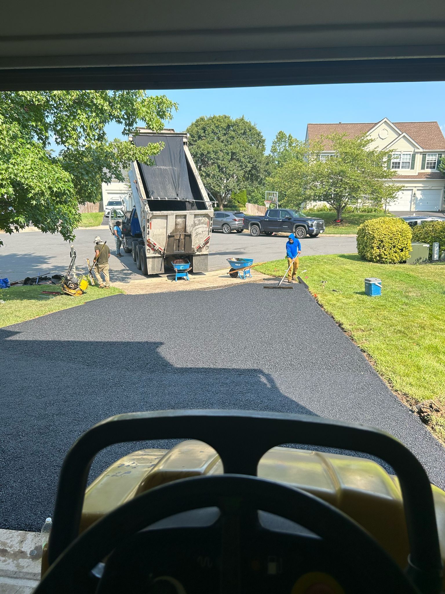 A view of a driveway being paved from inside a garage.