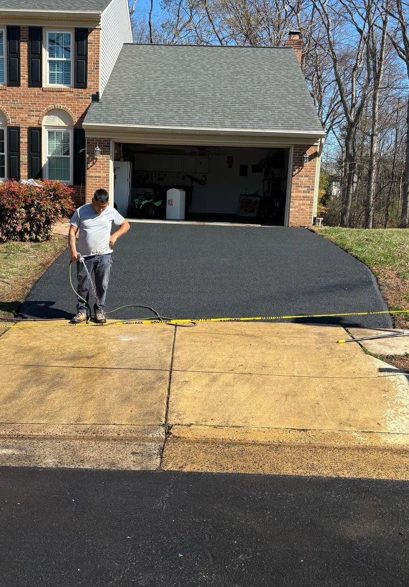 A man is standing in a driveway in front of a house.