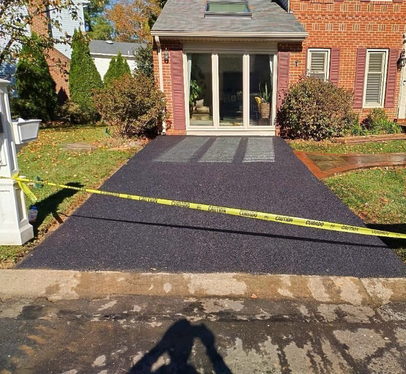 A brick house with a sliding glass door and a black driveway.